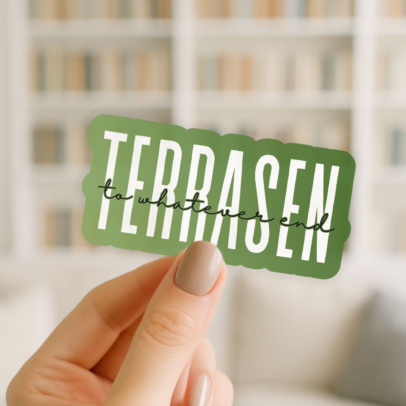 Hand holding a green sticker with 'TERRASEN' text against a blurred background