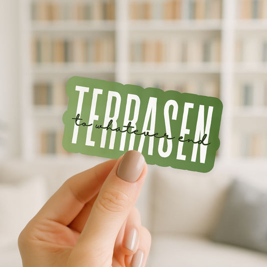 Hand holding a green sticker with 'TERRASEN' text against a blurred indoor background