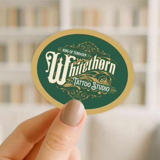 Hand holding a round sticker with 'Whitethorn Tattoo Studio' design.