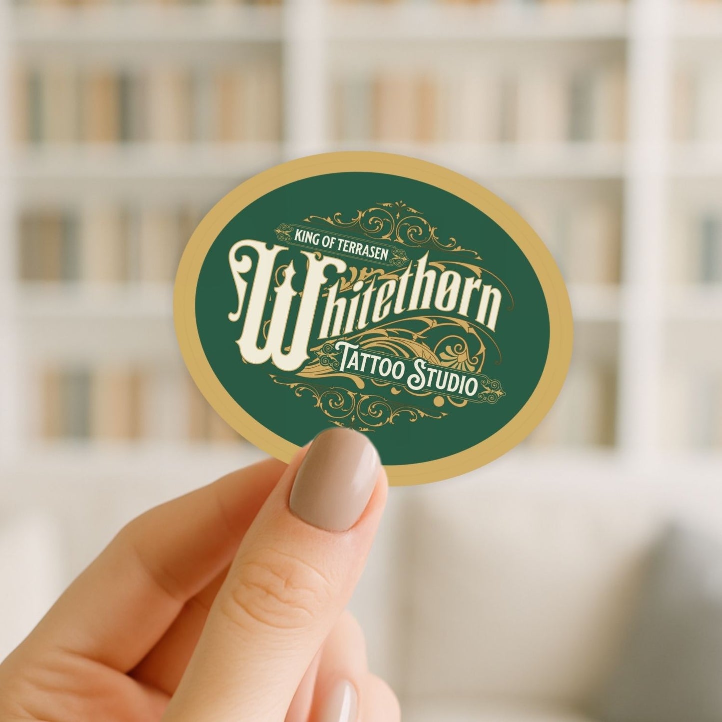 Hand holding a round green and gold sticker with 'Whitethorn Tattoo Studio' text.