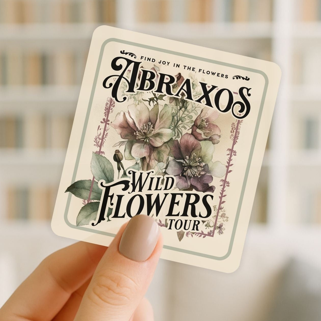 Card with floral design and text held by a hand against a blurred background