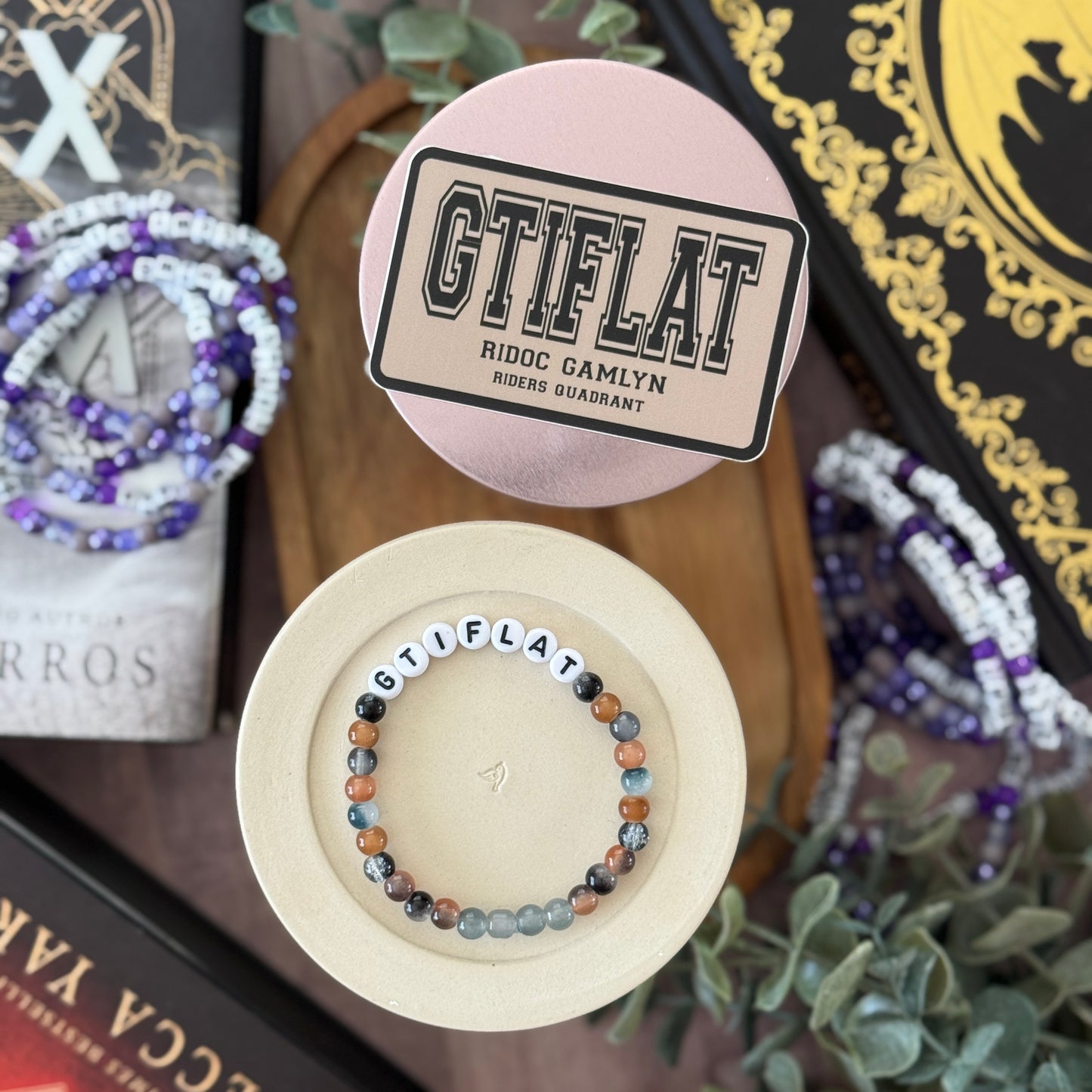 Bracelet with 'GTIFLAT' branding on a wooden surface with decorative items.
