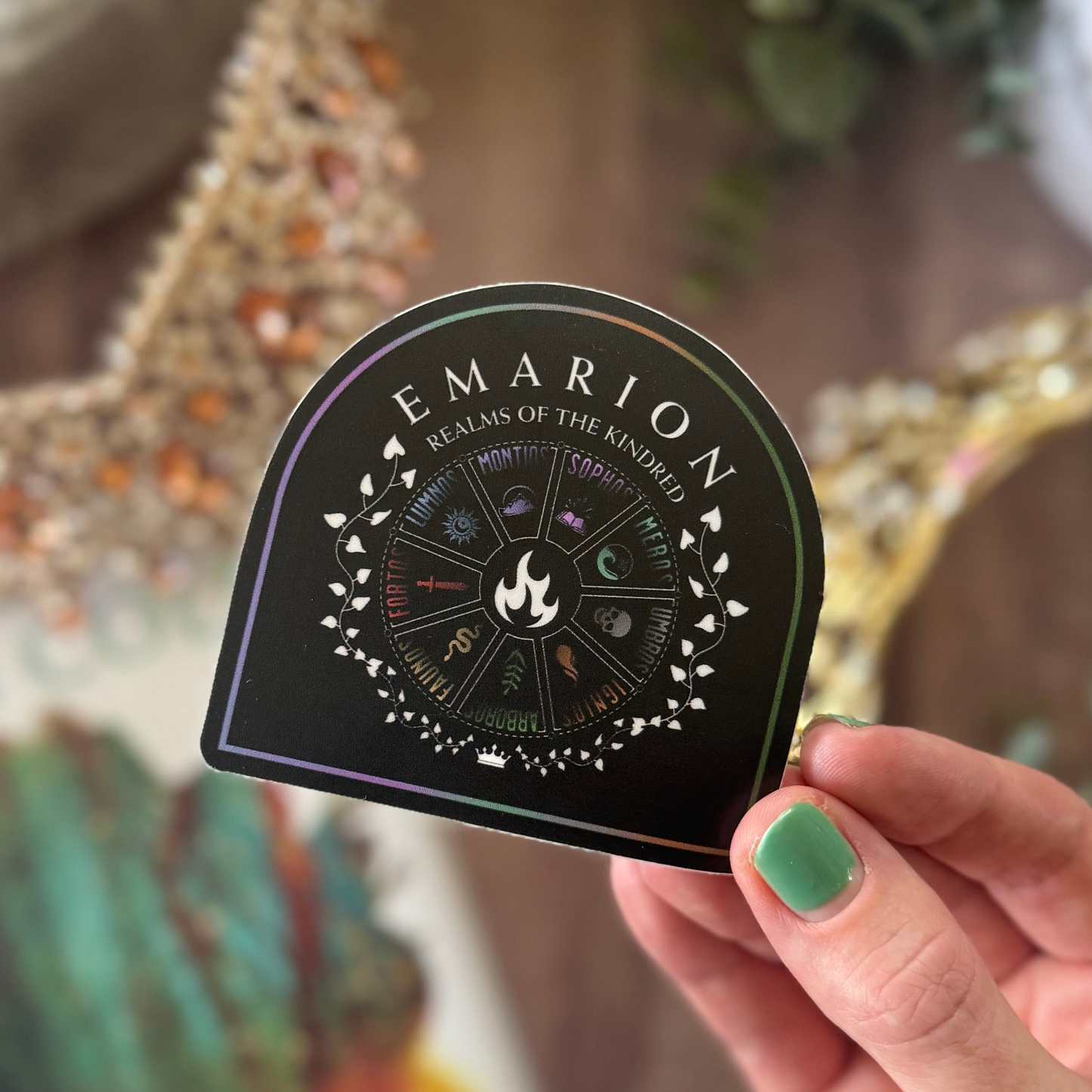 Hand holding a 'Emarion Realms of the Kindred' product with decorative background