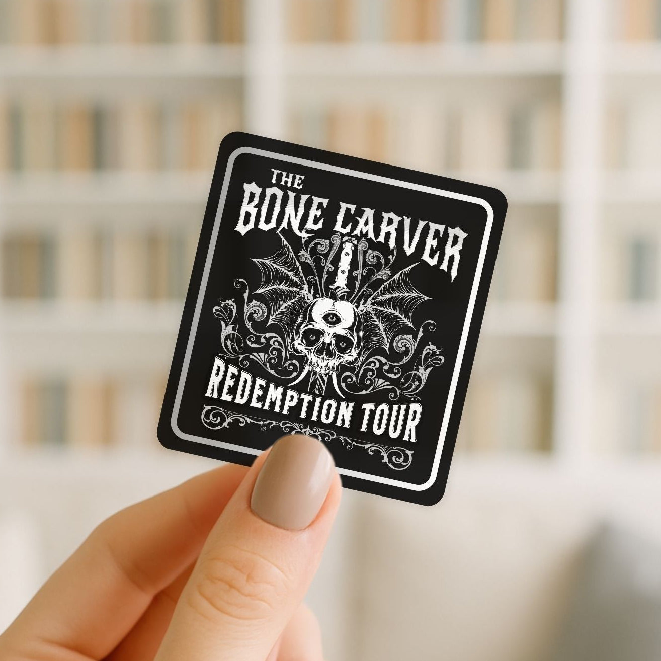 Sticker with 'The Bone Carver Redemption Tour' design held by a hand against a blurred background