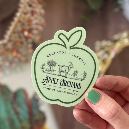 Hand holding a green sticker with 'Apple Orchard' design and text.