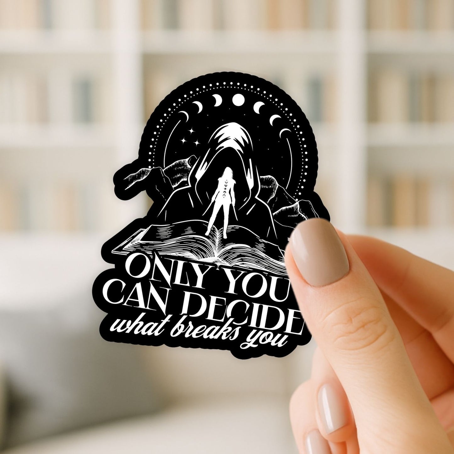 Hand holding a black and white motivational sticker with text and design.