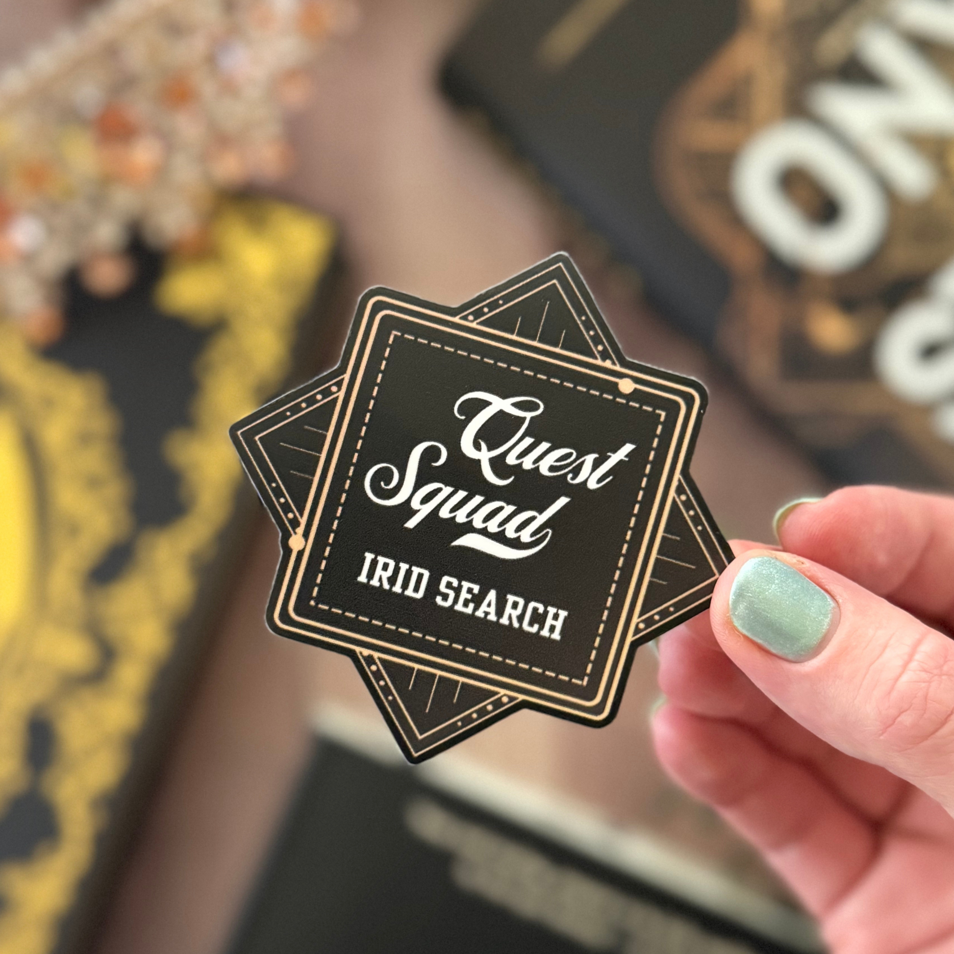 Hand holding a 'Quest Squad IRID SEARCH' sticker with blurred background