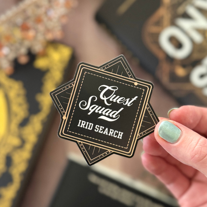 Hand holding a 'Quest Squad IRID SEARCH' sticker with blurred background