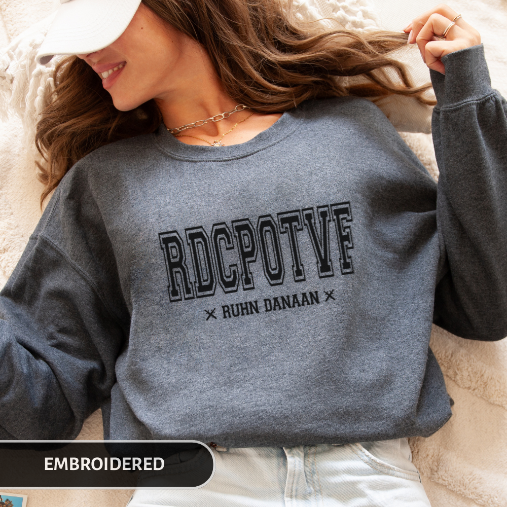 Person wearing a gray sweatshirt with 'RDCPOTF' text, lying on a soft surface.