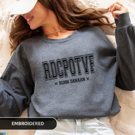 Person wearing a gray sweatshirt with 'RDCPOTF' text, lying on a soft surface.