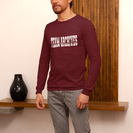 Man wearing a maroon long-sleeve shirt with text, standing against a wooden panel background.